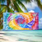 Tie-Dye Beach towel featuring two dolphins circling each other against a tie dye backdrop, hanging on a close line in an island paradise