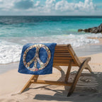 Seashell peace sign beach towel placed over a wooden lounge chair next to the ocean