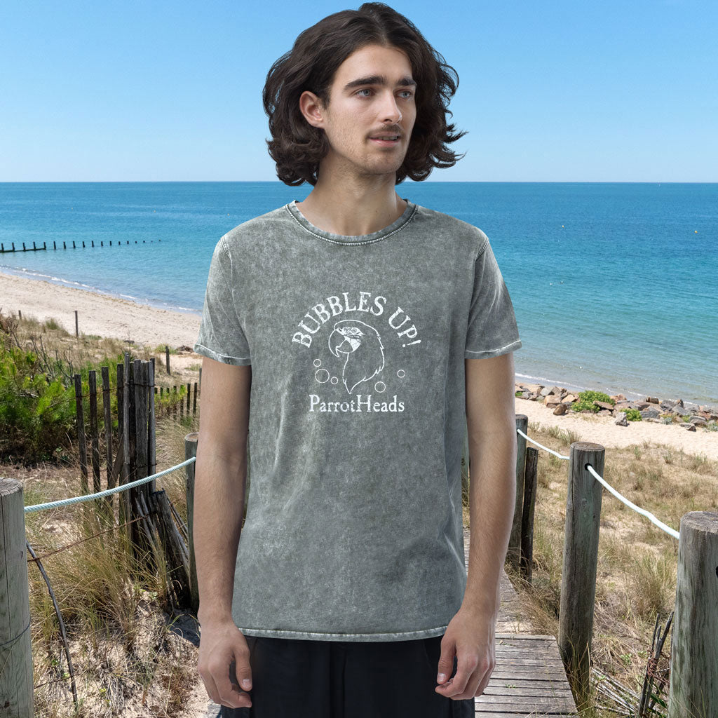 Person wearing a ParrotHeads Denim T-Shirt with 'Bubbles Up! ParrotHeads' text and graphic on a beach