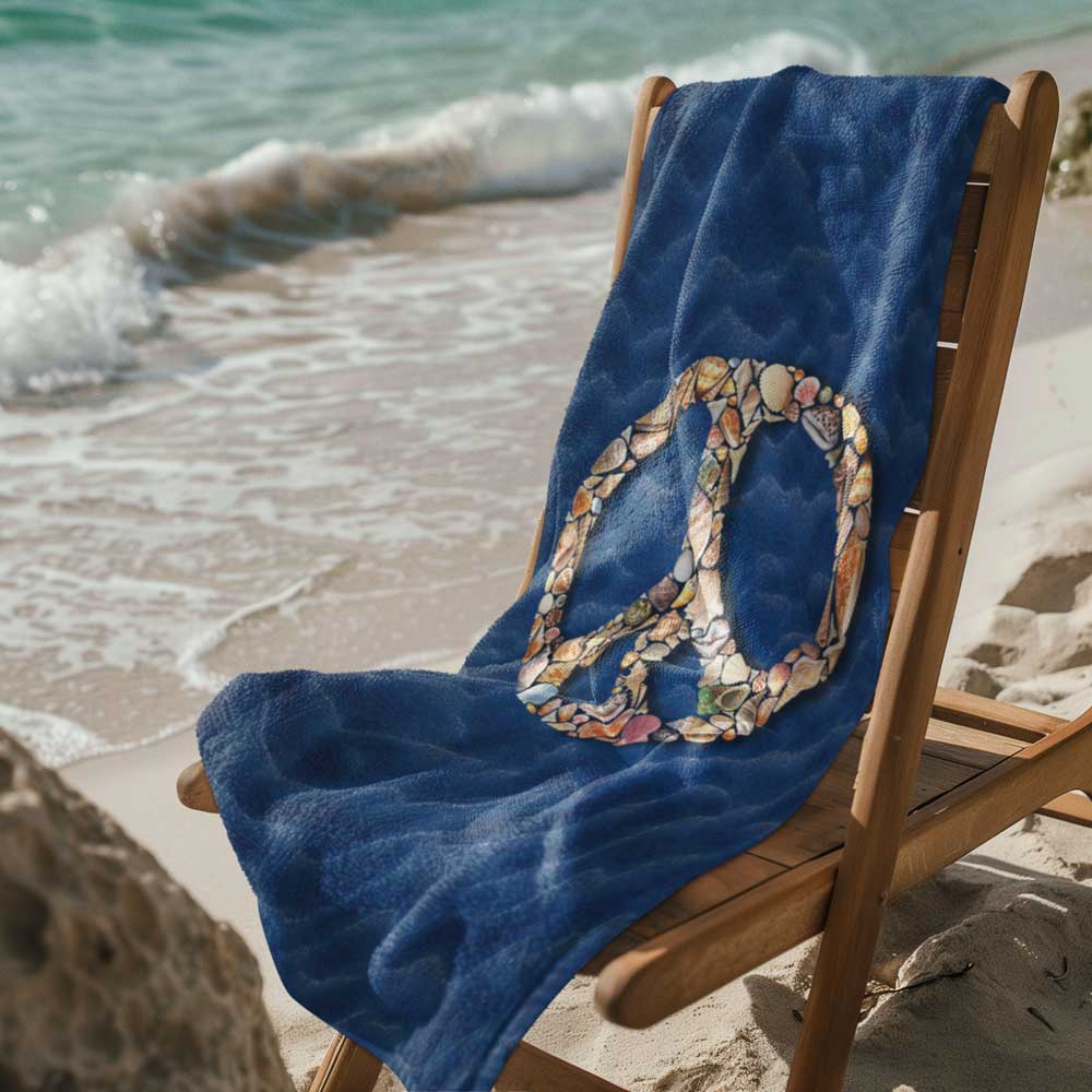 Blue Beach towel featuring a peace sign made of seashells draped over a wooden deck chair