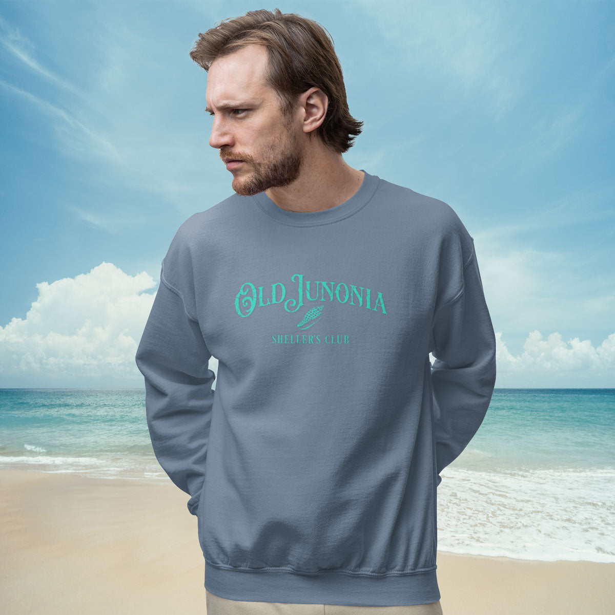 Man wearing a gray sweatshirt with 'Old Junonia' logo on a beach