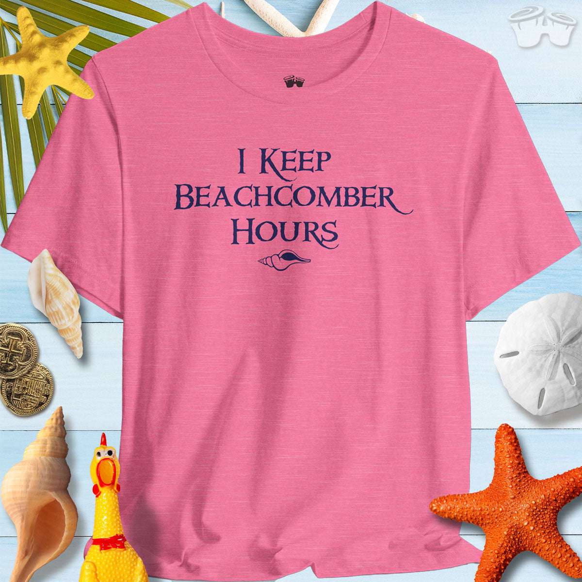 Beachy Bella Shelling T-Shirt in pink with 'I Keep Beachcomber Hours' text, surrounded by seashells and beach decor.