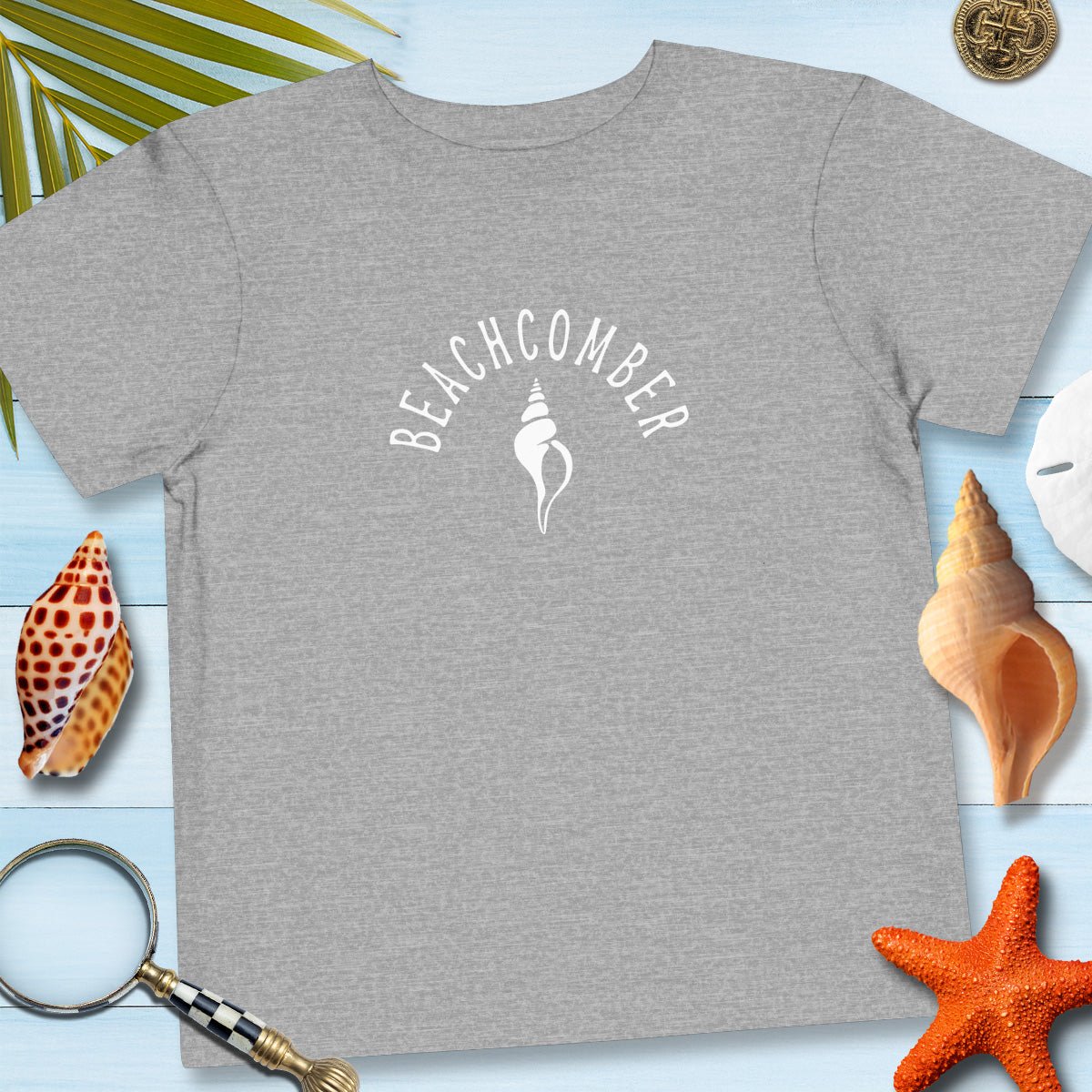 Athletic gray Toddler Tee with beachcomber arched over a shell