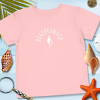 Pink t-shirt with 'BEACHCOMBER' text and shell graphic on a blue surface with beach-themed items.