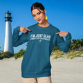 Person wearing a blue ParrottHead sweatshirt with text on a beach with a lighthouse in the background