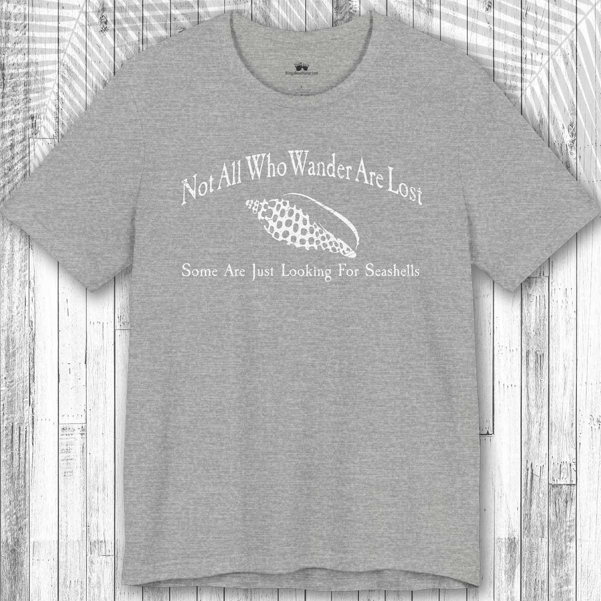 Gray t-shirt with white text and seashell graphic on a wooden surface