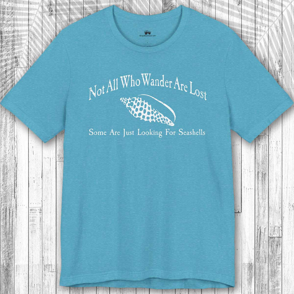 Blue Wanderlust t-shirt with white text and seashell graphic on a wooden surface