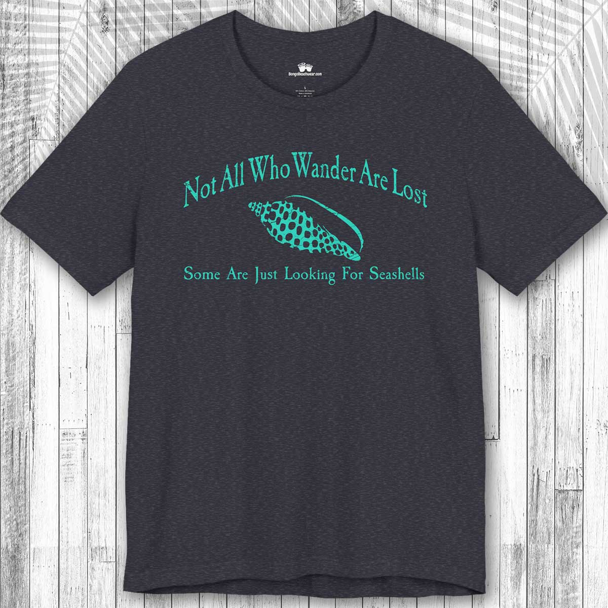 Navy blue Wanderlust t-shirt with teal text and seashell graphic on a wooden surface