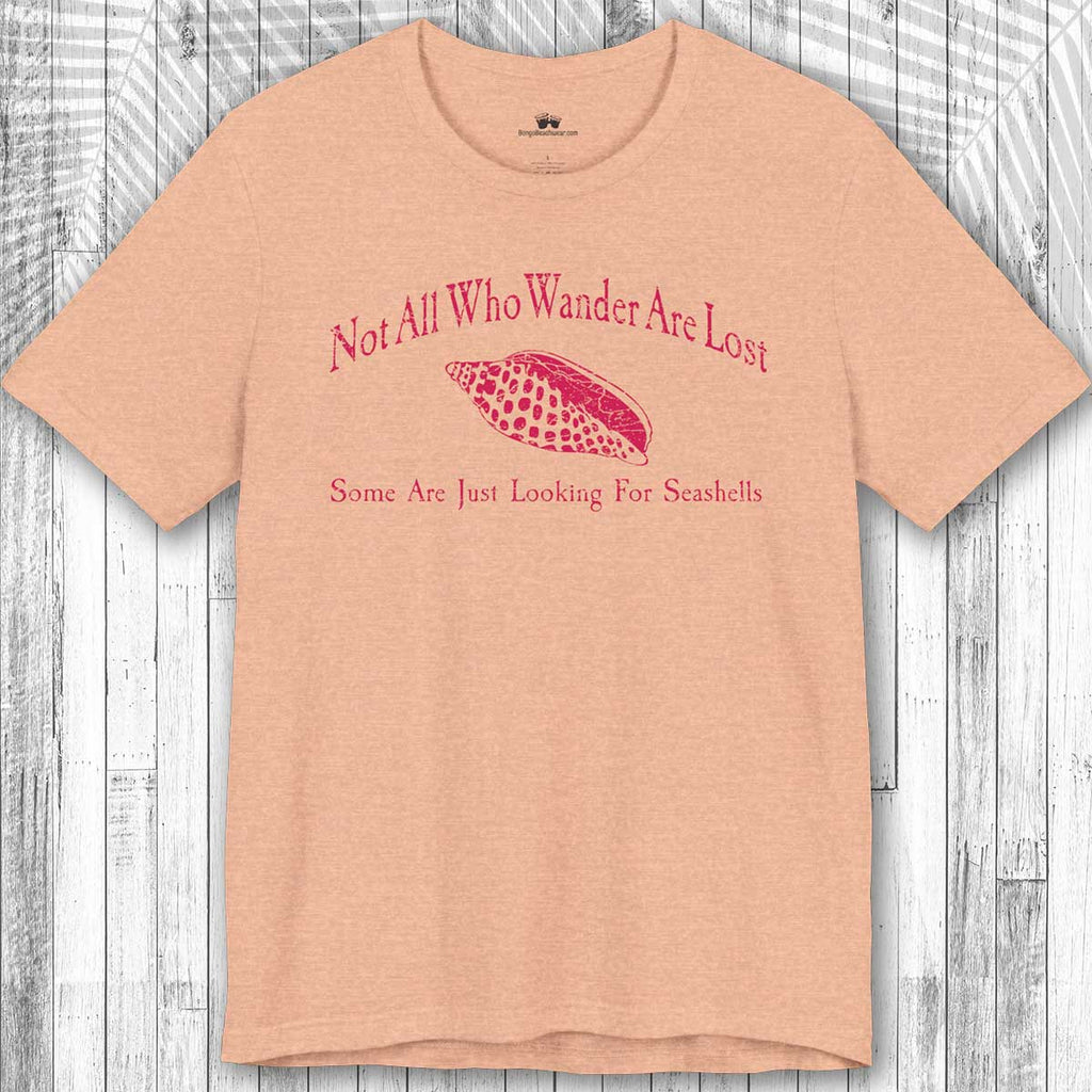 Beige t-shirt with red text and seashell graphic on a wooden surface