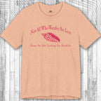 Beige t-shirt with red text and seashell graphic on a wooden surface