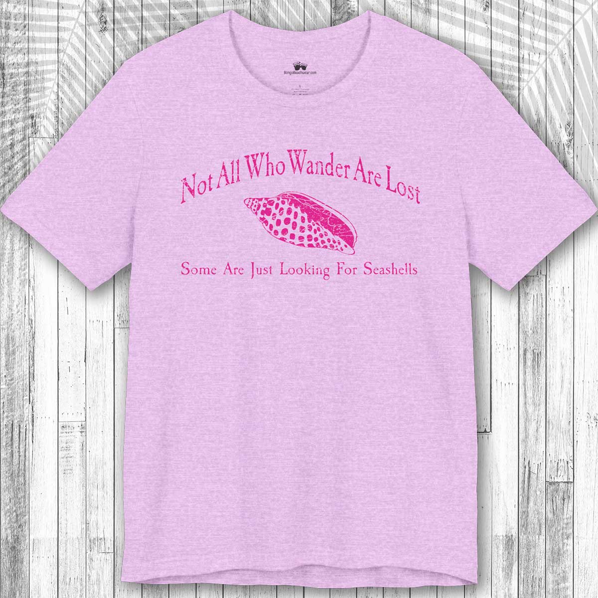 Purple t-shirt with pink text and seashell graphic on a wooden surface