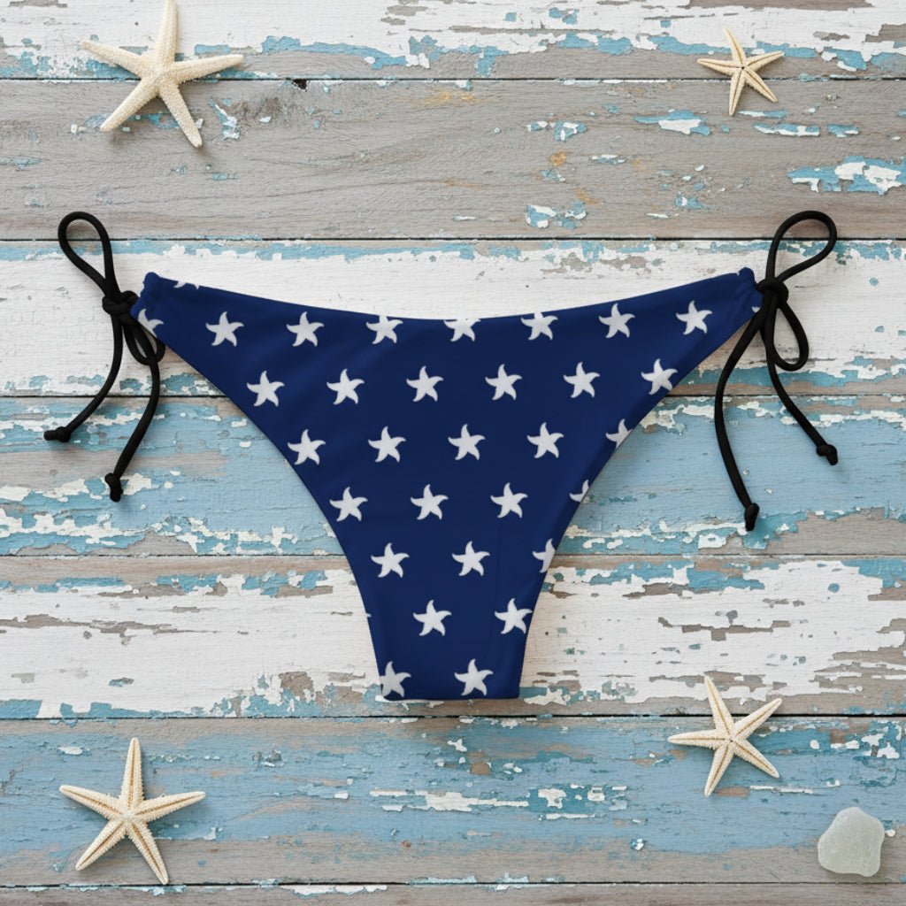 Navy blue bikini bottom with white star pattern on a beach.