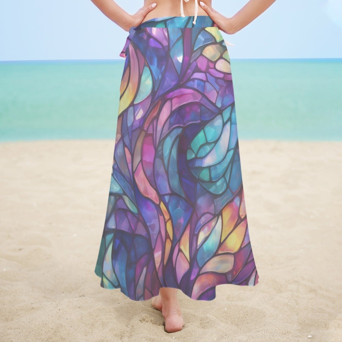 Person wearing a colorful stained glass patterned sarong on a beach.