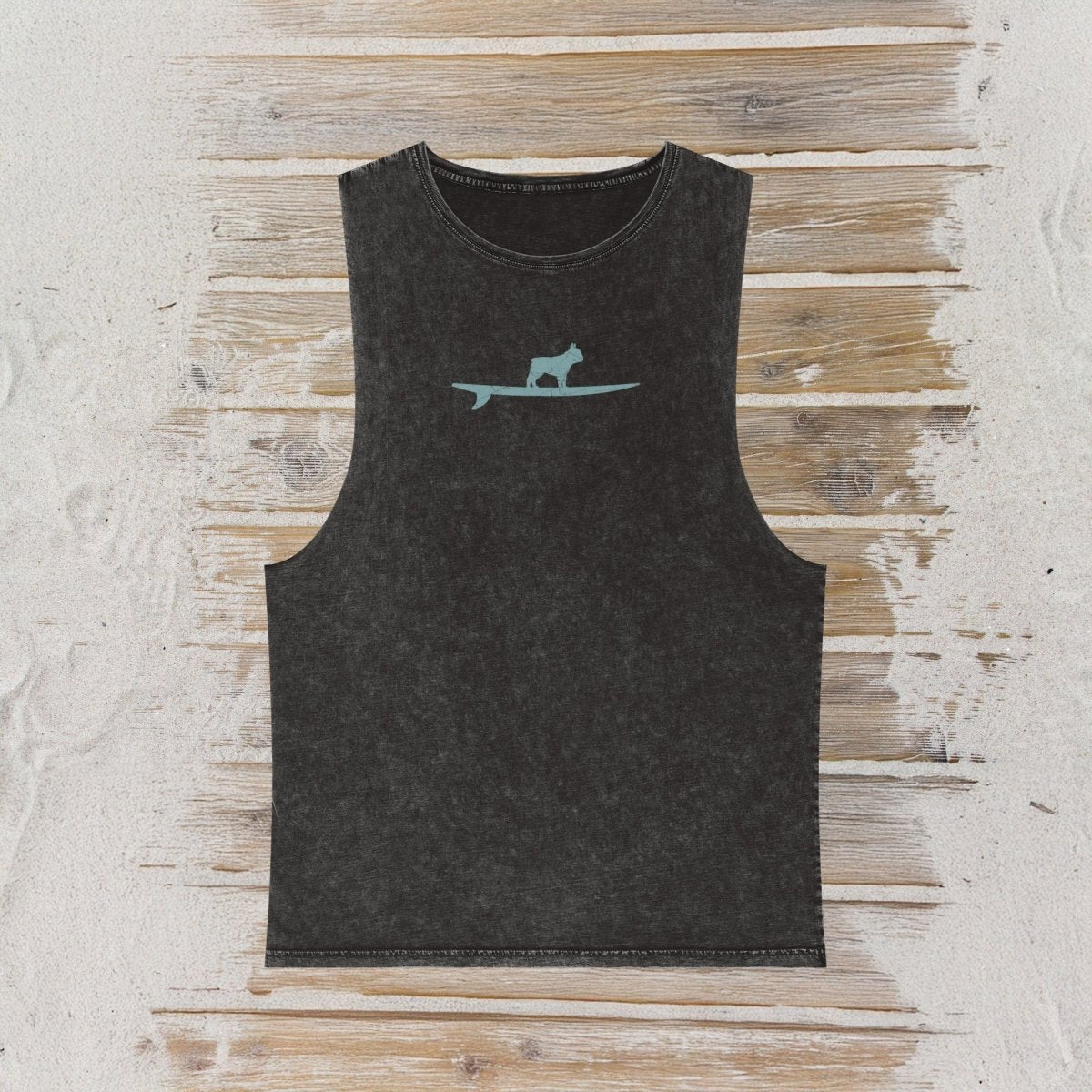 A dark charcoal gray sleeveless tank top with a small light blue graphic of a dog on a surfboard on the chest, laid flat on a rustic wood background.