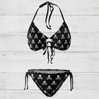 Black bikini set with skull and crossbones pattern on a white nautical wood background