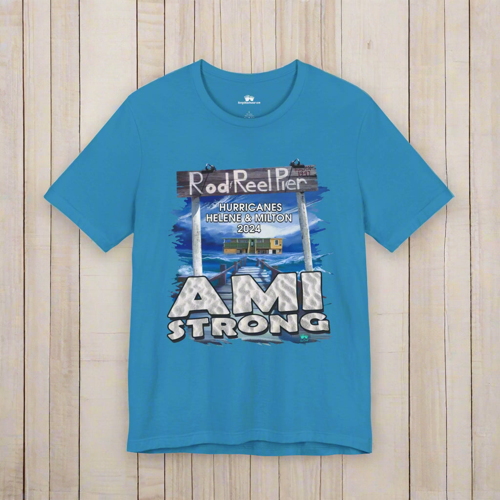 Blue t-shirt with 'Rod Reel Pier' and 'AMI Strong' graphic on a rustic nautical wood background