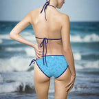 sexy women in a bikini standing on the beach facing the ocean