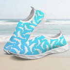 A pair of slip-on water shoes featuring a bright turquoise blue upper covered in a white dolphin pattern, with white soles, shown on a clean white background.