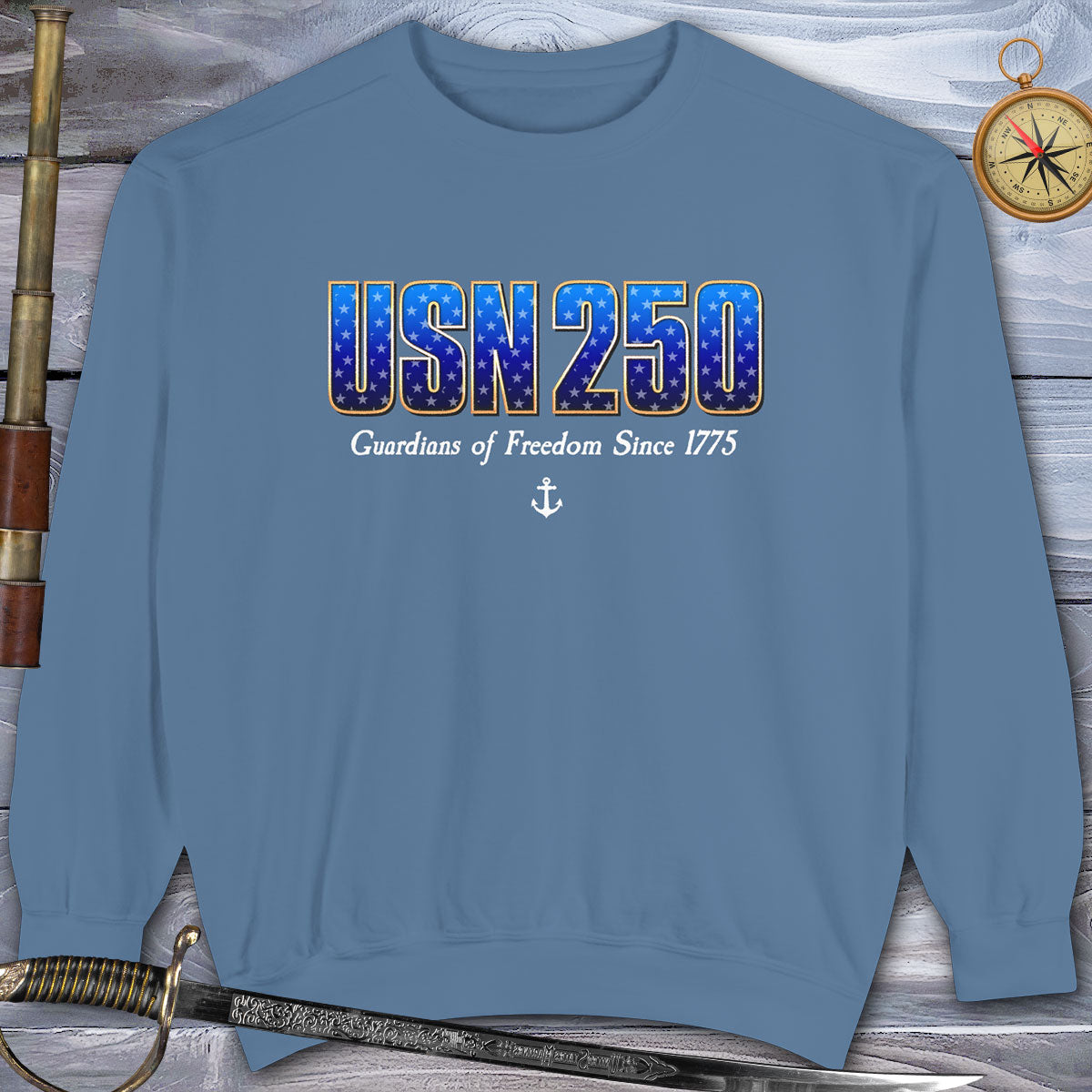 Blue sweatshirt with 'USN250 Guardians of Freedom Since 1775' text on a wooden background
