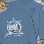 Blue sweatshirt with United States Navy 250th Anniversary design on a wooden surface.