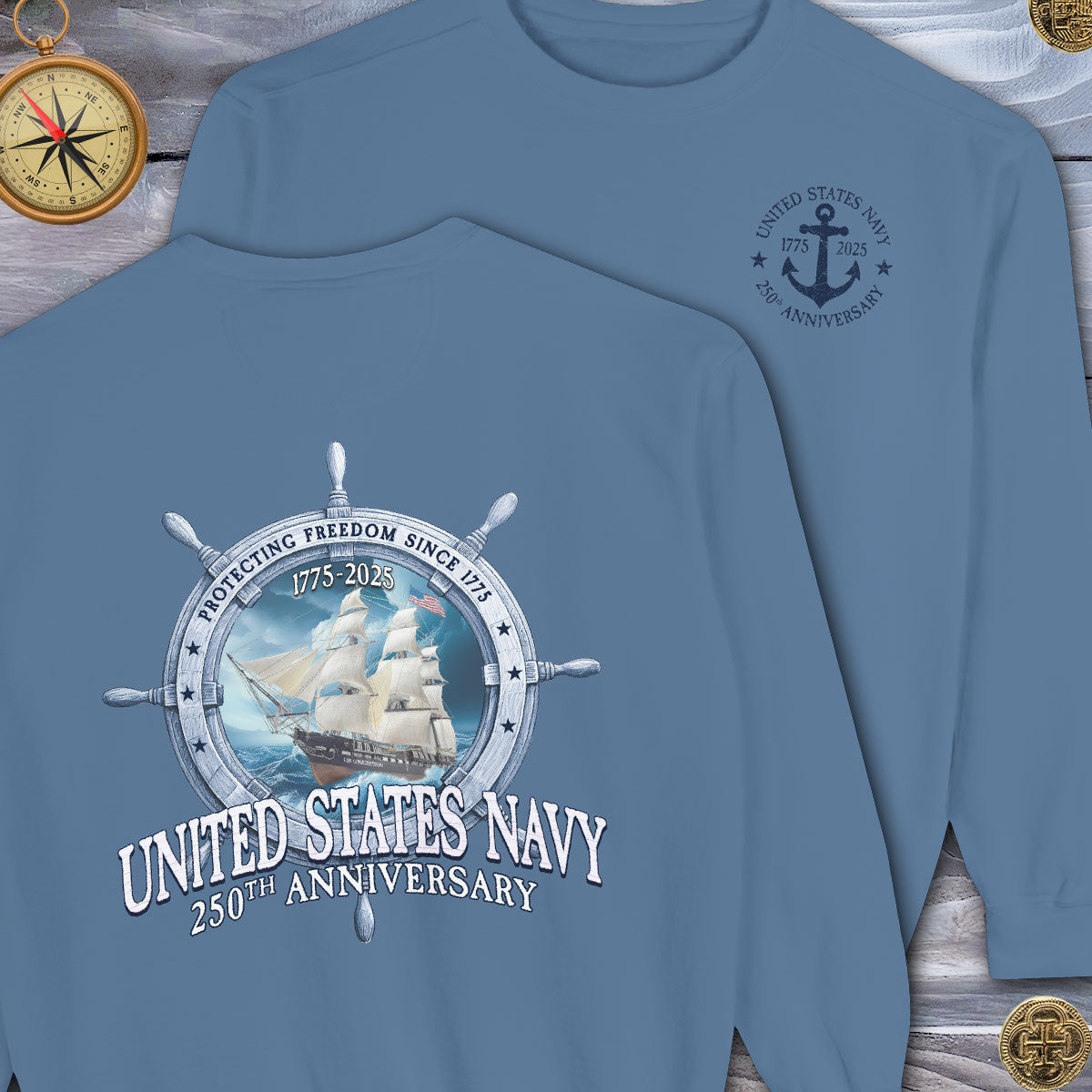 Blue sweatshirt with United States Navy 250th Anniversary design on a wooden surface.