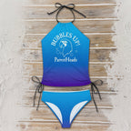 Blue and purple bikini set with 'Bubbles Up! ParrotHeads' text on a sandy beach boardwalk/