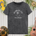Black t-shirt with 'Bubbles Up! ParrotHeads' design on a wooden background with tropical elements.