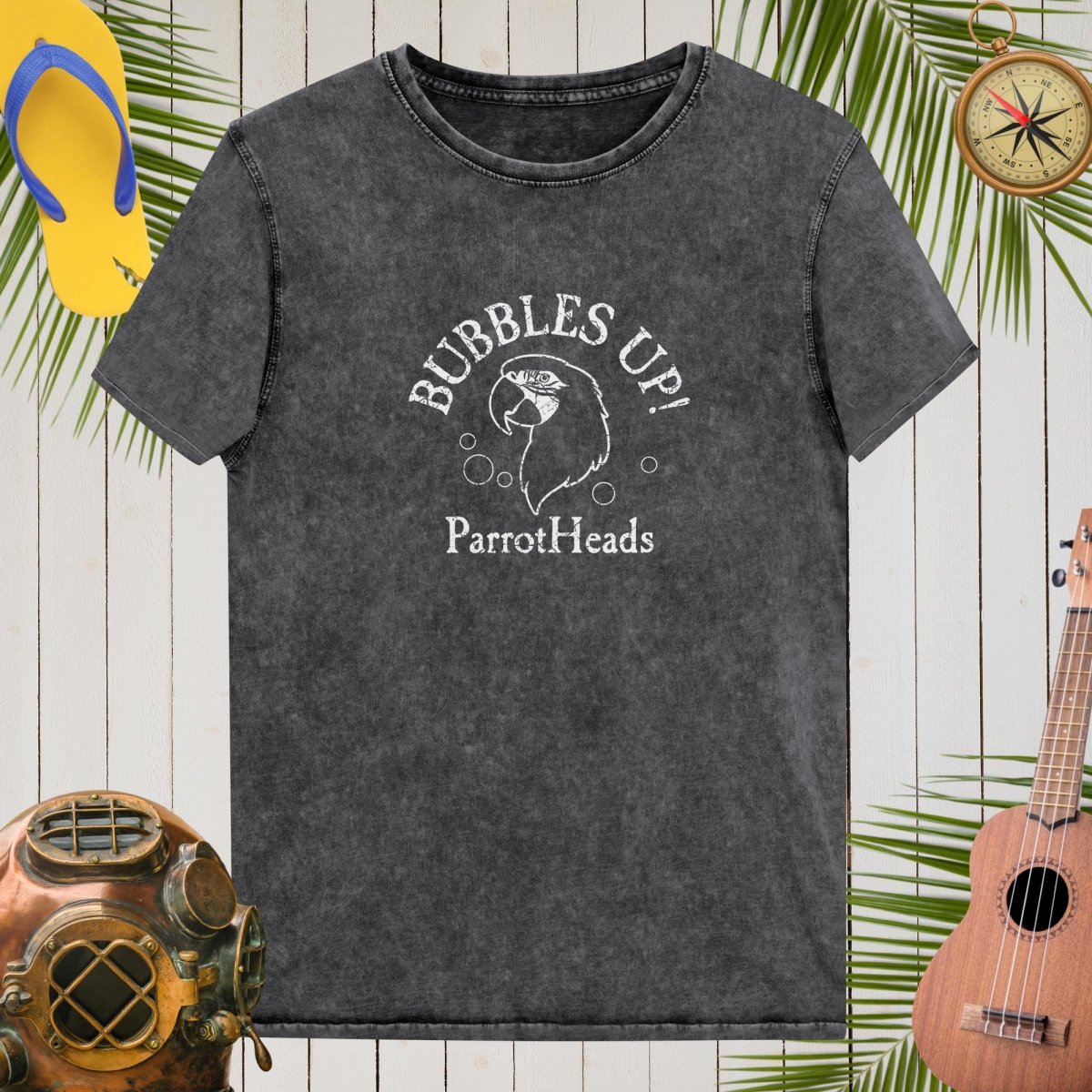 Black t-shirt with 'Bubbles Up! ParrotHeads' design on a wooden background with tropical elements.