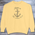 Yellow sweatshirt with anchor design and text on a wooden surface