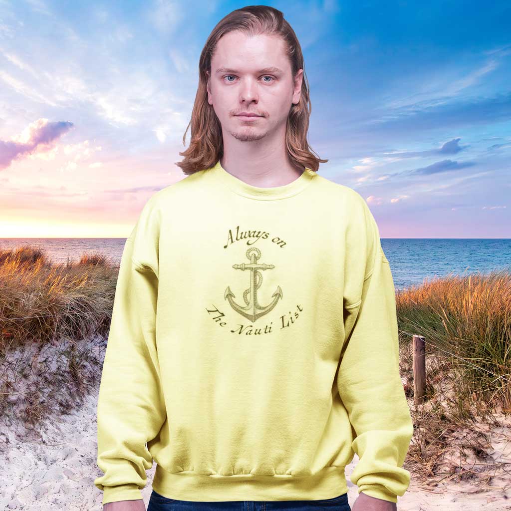 Person wearing a butter-yellow sweatshirt with an anchor design on a beach