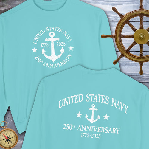 Two light blue t-shirts with United States US Navy Anniversary design on a wooden background with a ship's wheel and compass.