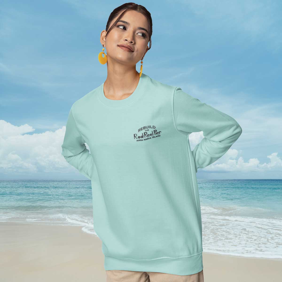 Woman wearing a light blue sweatshirt with text on a beach
