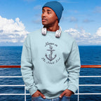 Person wearing a light blue sweatshirt with an anchor design and text, "Always on the Nauti List standing on a boat with ocean and sky in the background.