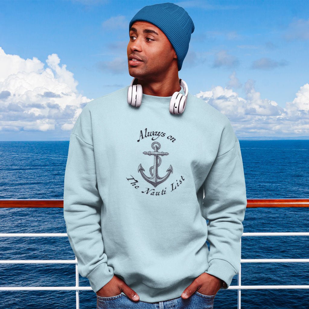 Person wearing a light blue sweatshirt with an anchor design and text, "Always on the Nauti List standing on a boat with ocean and sky in the background.