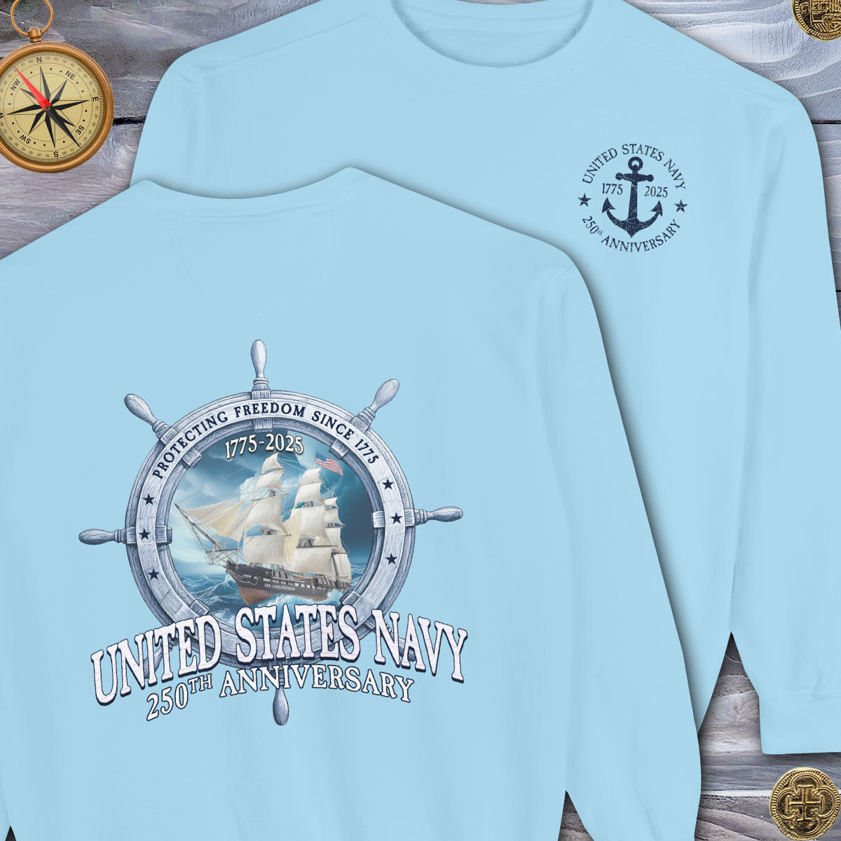 Light blue t-shirt with United States Navy 250th Anniversary design on a wooden surface.