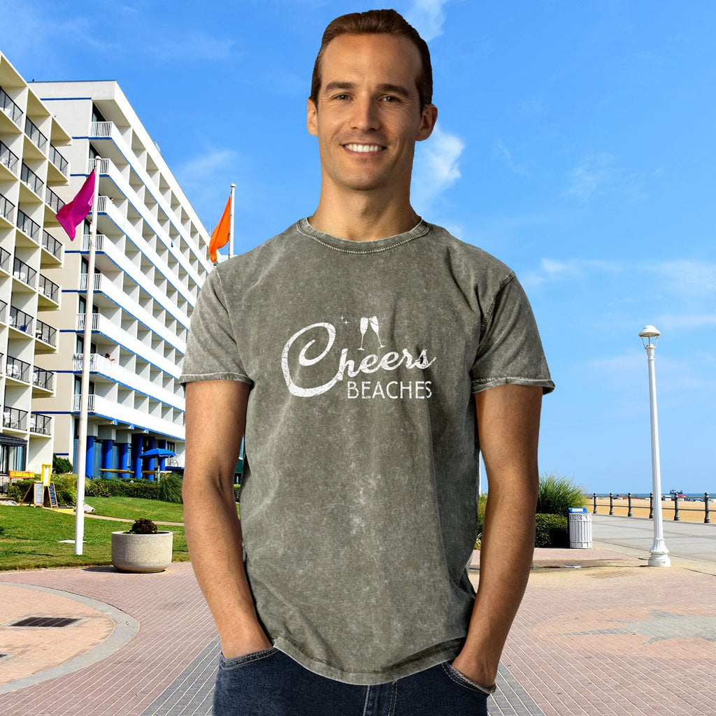 Man wearing a 'Cheers Beaches' t-shirt standing in front of a building with a blue sky.