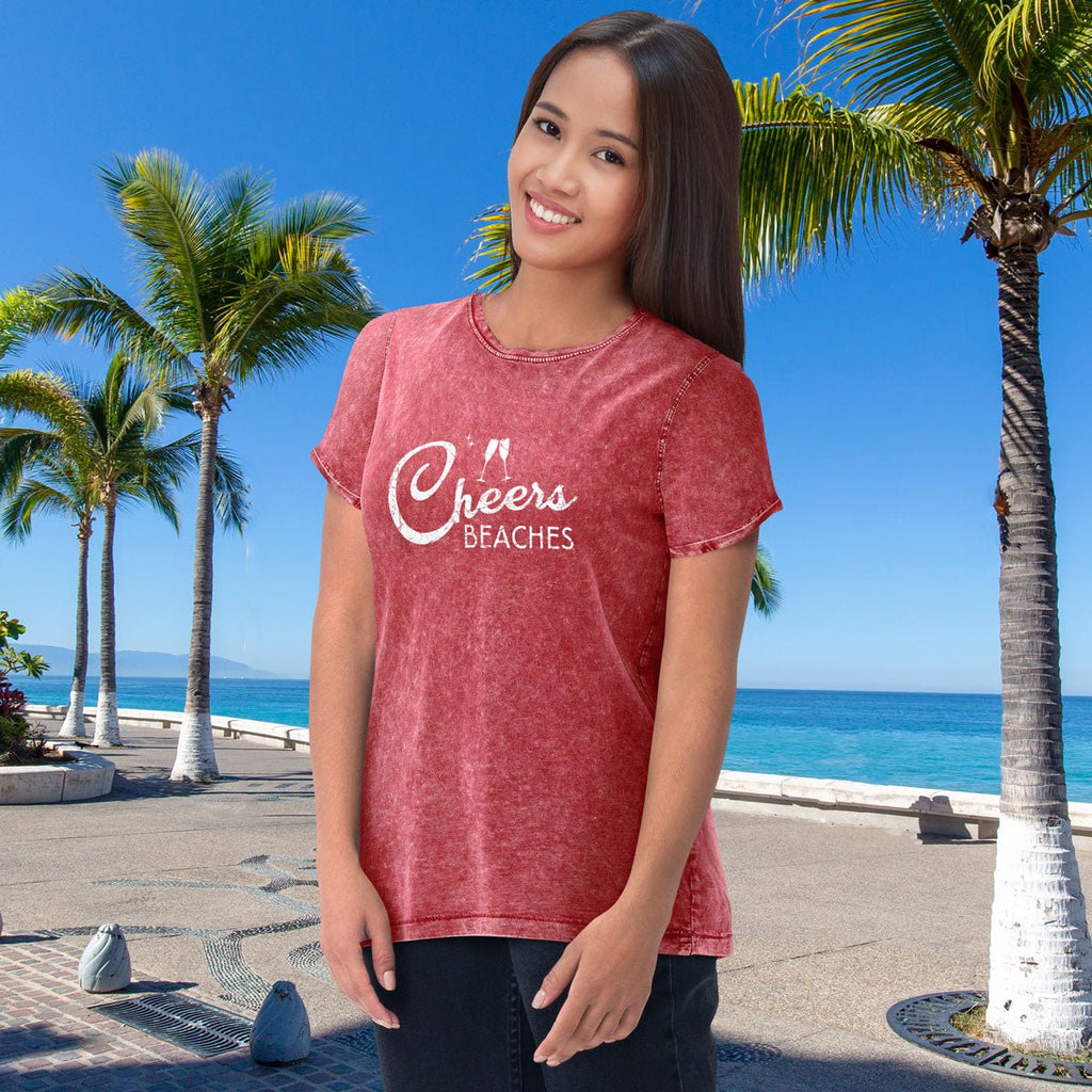 Woman wearing a red cheers beaches denim t-shirt with palm trees and ocean in the background