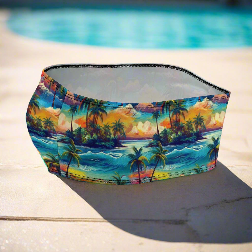 Bandeau Swim top with tropical island design sitting upright next to a pool