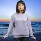 Person wearing a gray sweatshirt with 'Old Junonia' logo on a beach at sunset