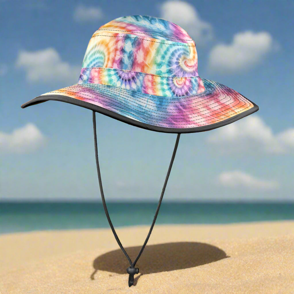 Colorful tie-dye bucket hat with a black chin strap on a beach background