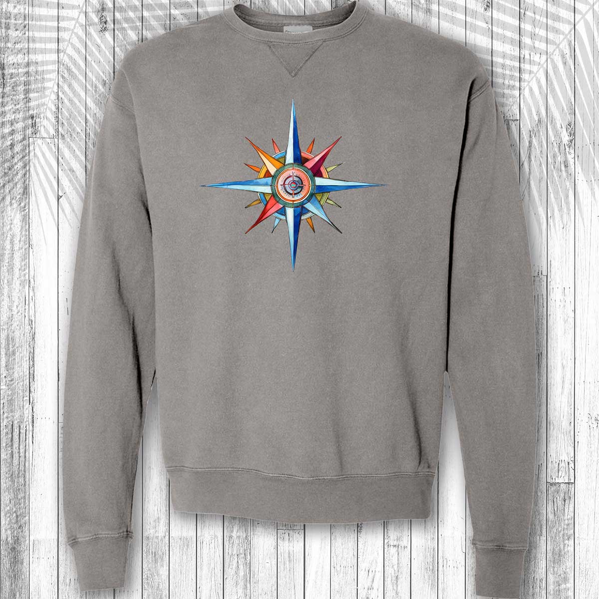 Gray sweatshirt with a colorful compass design on a wooden background