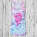 A women's racerback tank top featuring a pastel tie-dye pattern in pink, purple, and blue, with a large pink mermaid graphic printed on the front.