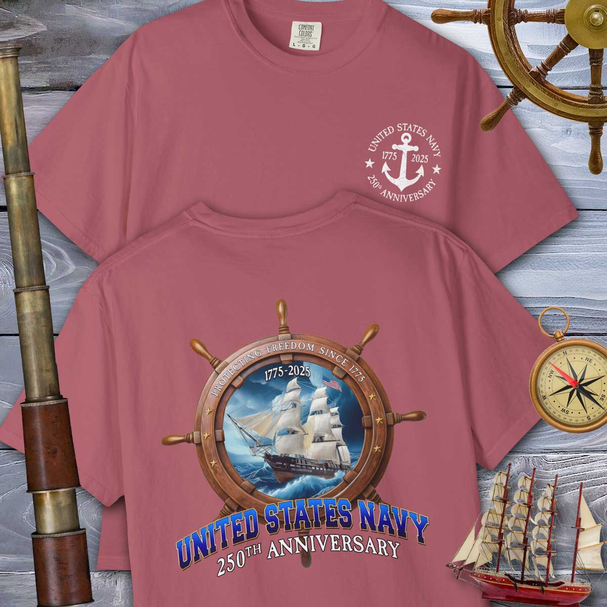 Two maroon t-shirts with United States Navy 250th Anniversary designs on a wooden background with ship and compass elements.