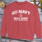 Red Go Navy Sweatshirt with 'Go Navy Beat Army It's Tradition' text on a wooden background with nautical items.