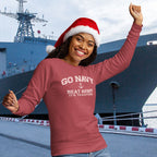Person wearing a crimson 'Go Navy Beat Army It's Tradition' sweatshirt and Santa hat in front of a navy ship.