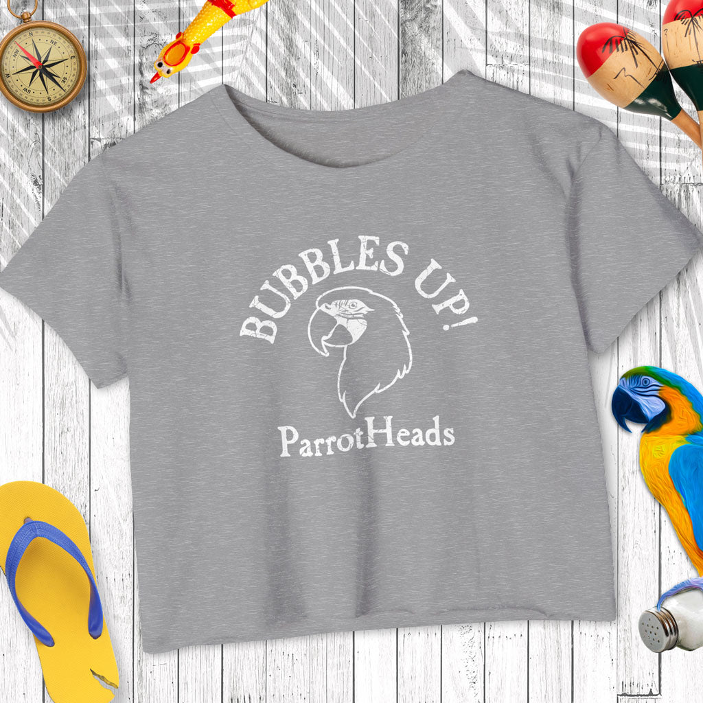 Gray t-shirt with 'Bubbles Up! ParrotHeads' text on a wooden surface with parrot-themed accessories.