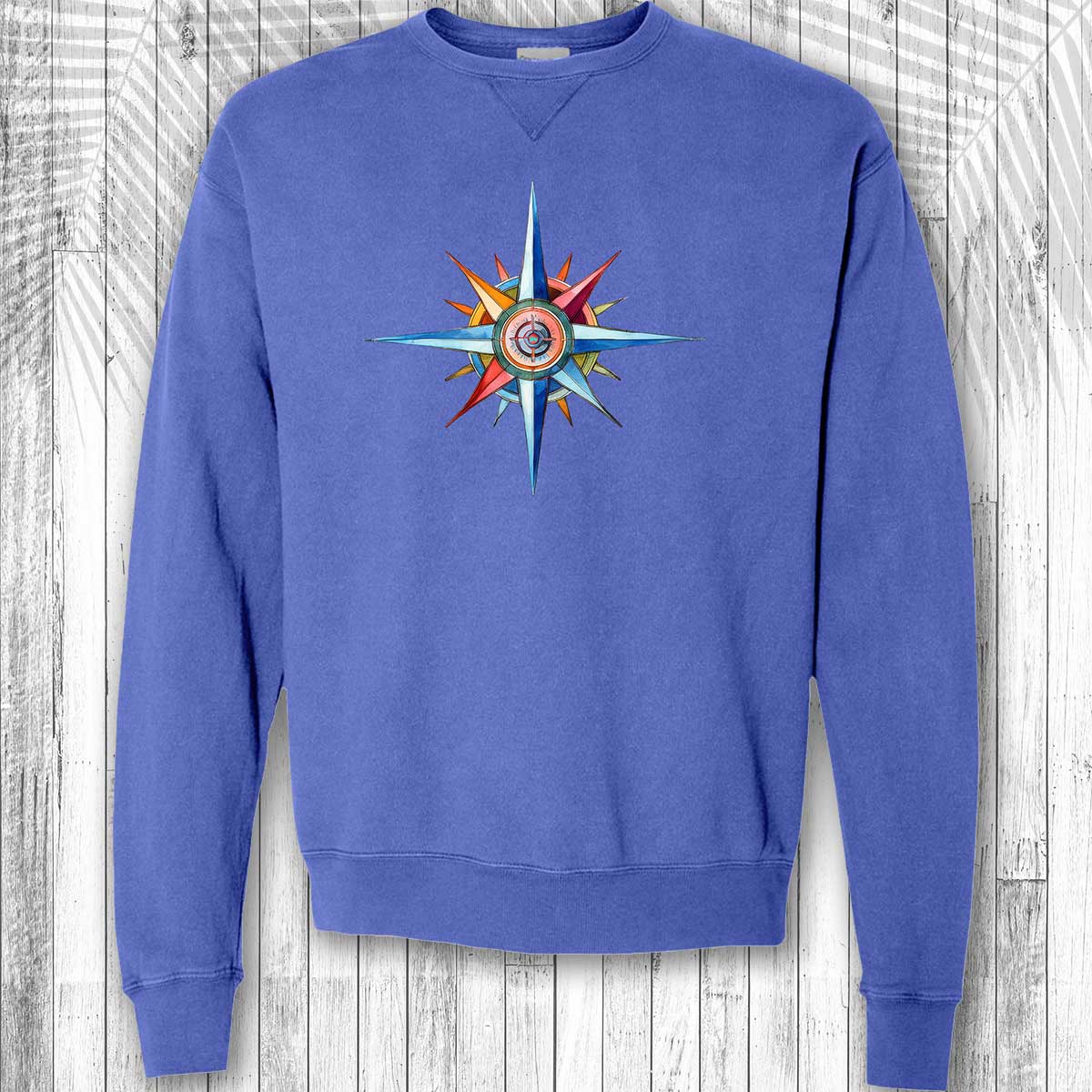 Blue sweatshirt with a colorful compass design on a wooden background
