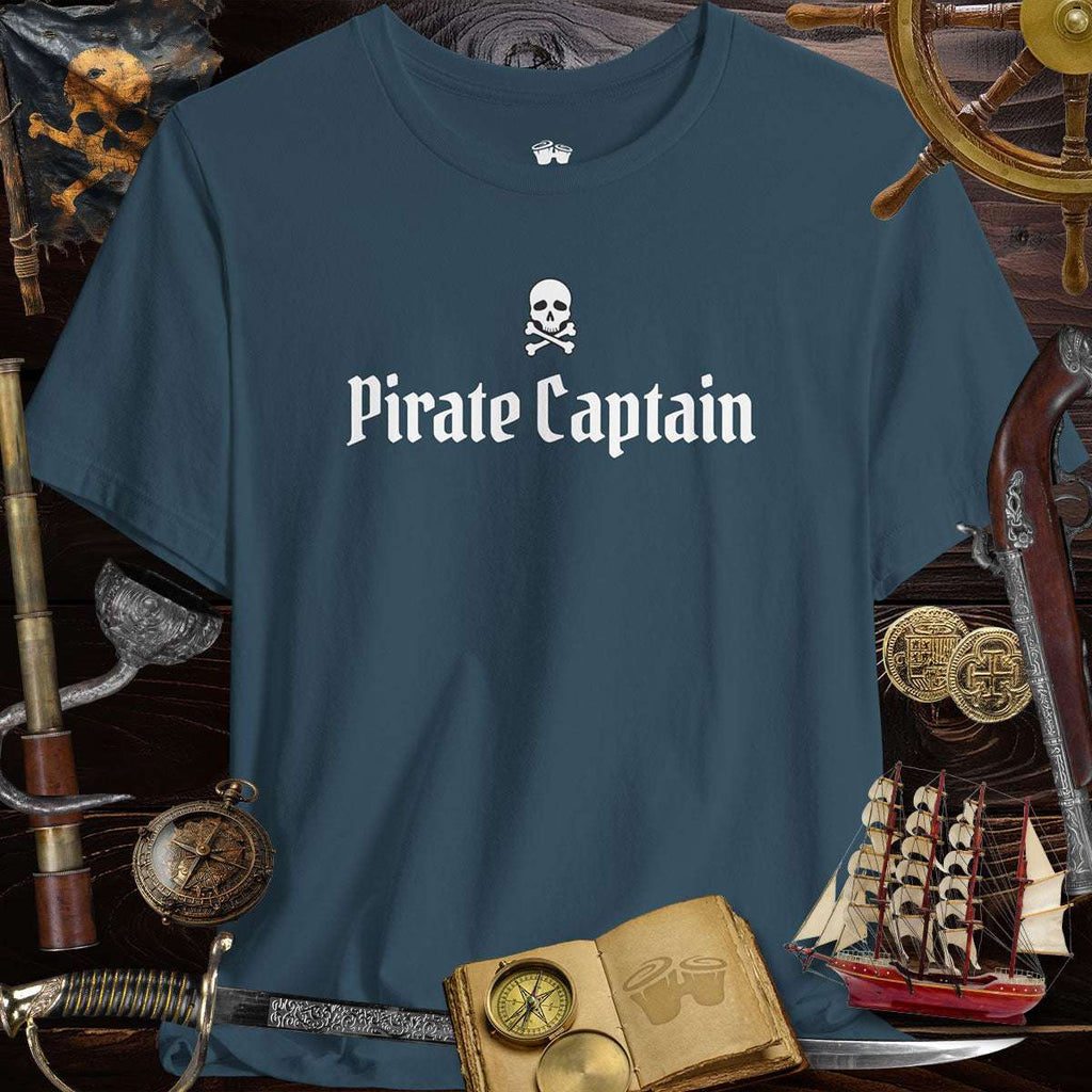 Pirate Captain unisex tee on a wooden table with pirate-themed items, perfect for adventure lovers.