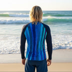 Person wearing a long-sleeve rash guard with a colorful striped pattern on the back, on Delray Beach