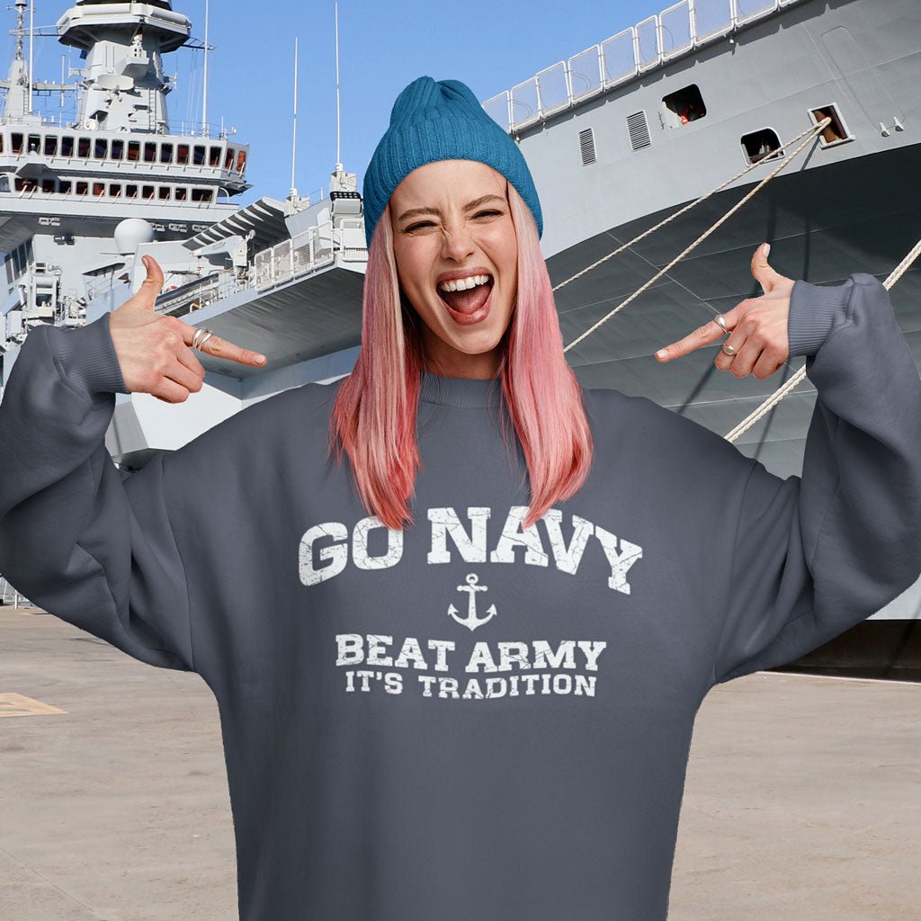 Person wearing a 'Go Navy Beat Army It's Tradition' sweatshirt in front of a navy ship.